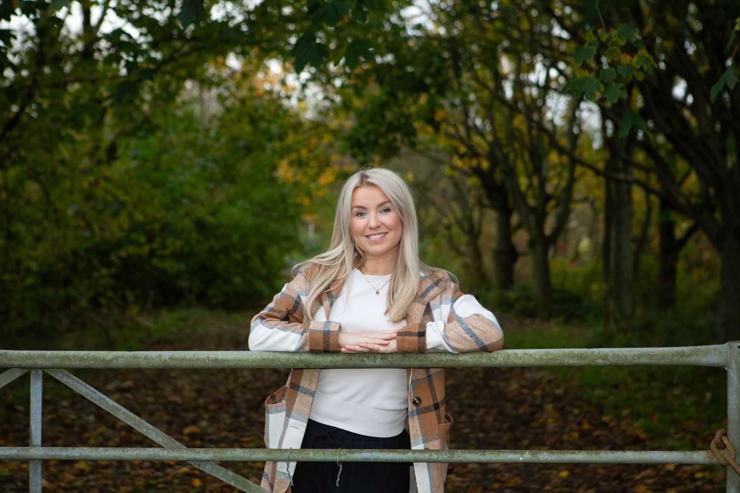 Kate leaning on a gate in nature